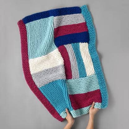 finished project from comforter blanket knitting pattern in turqouise navy white and maroon yarn
